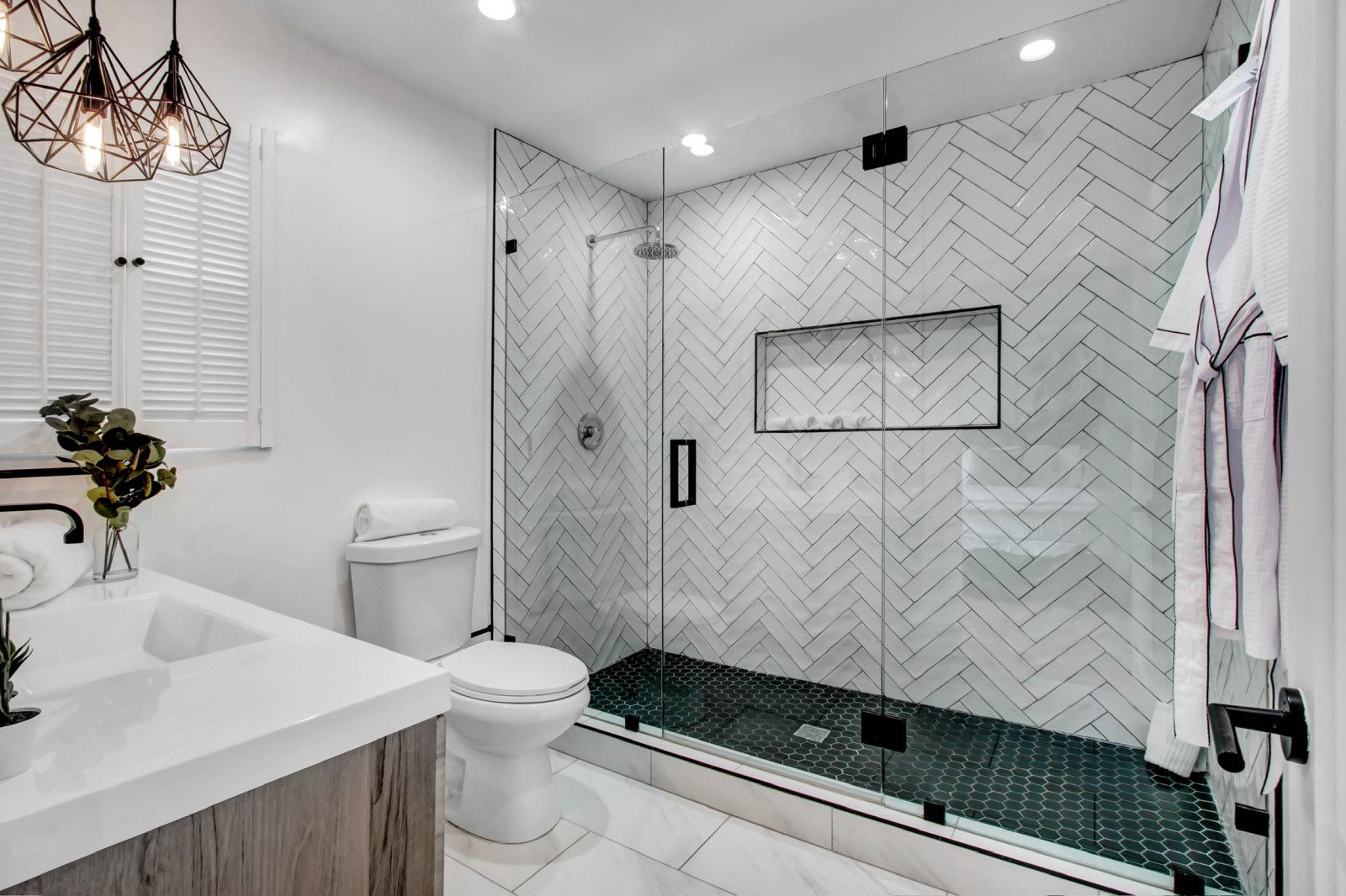 Walk-in shower with herringbone tile and frameless glass