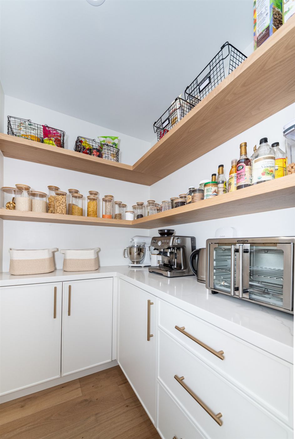 Organized pantry with open wooden shelves and brass hardware