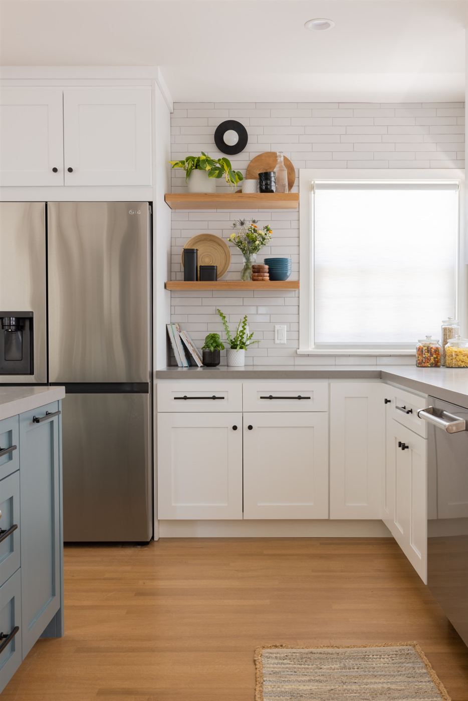 Kitchen with white and blue cabinets, black hardware and white subway tile backsplash